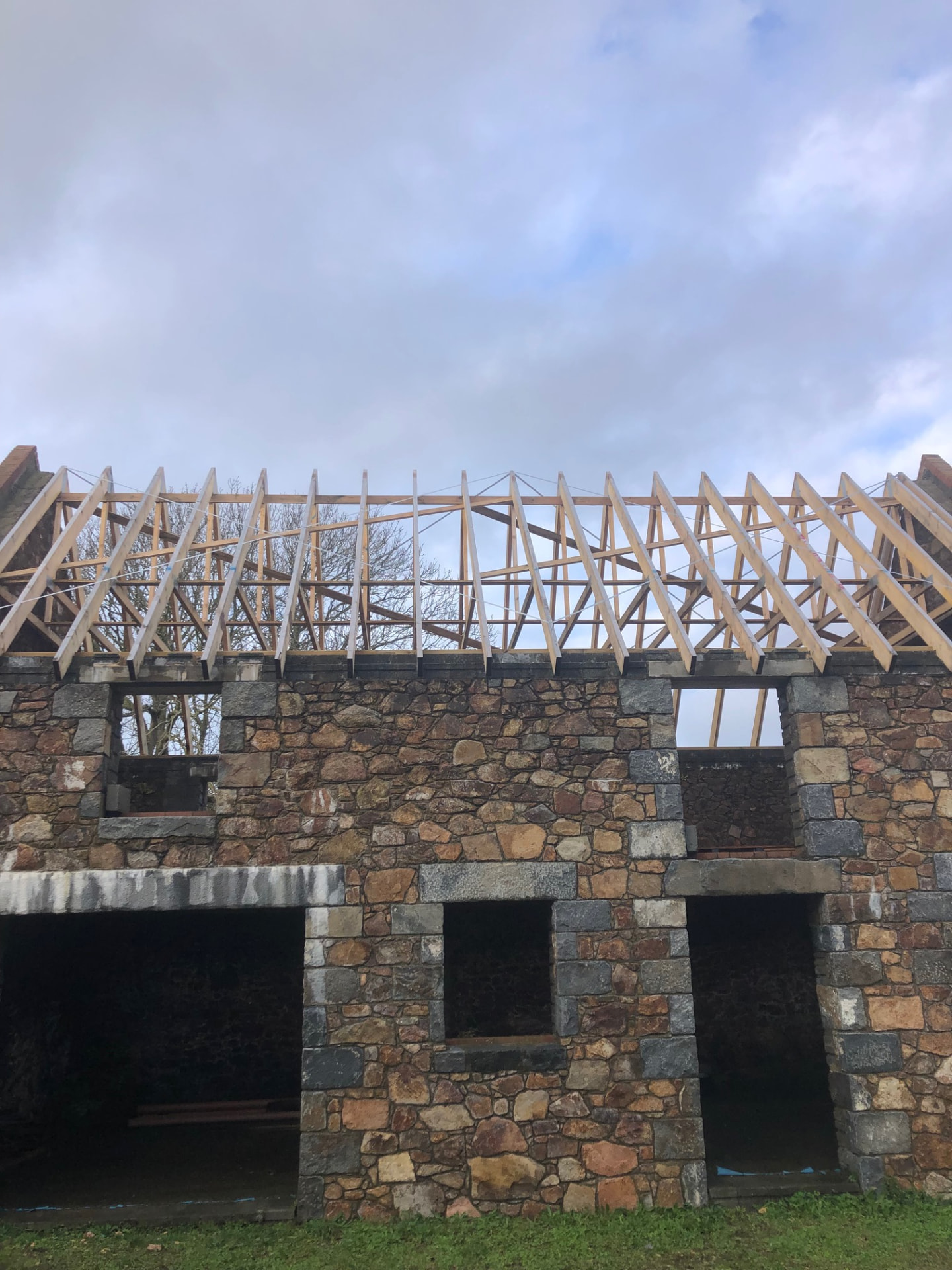 New roof trusses set out on the restored stone barn walls