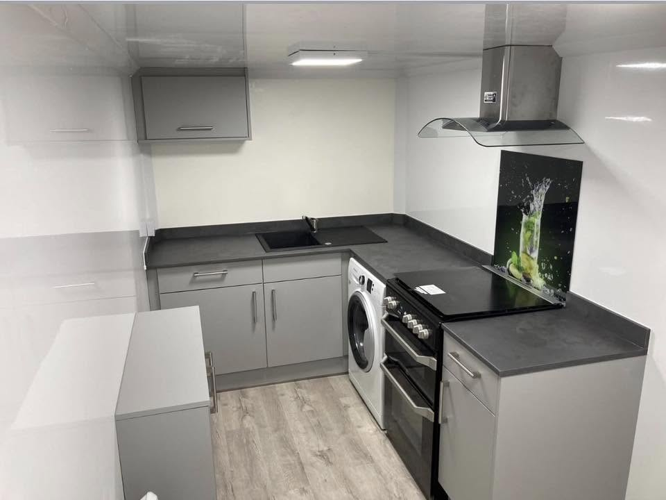 Inside a temporary kitchen pod with cooker, sink and washing machine
