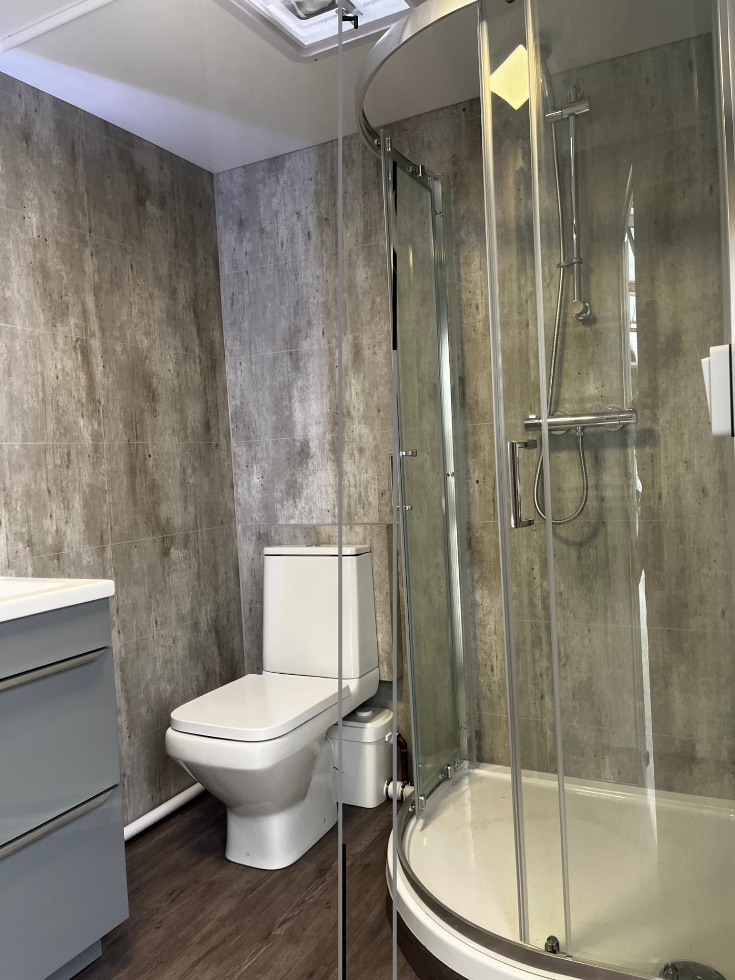 Inside a temporary shower pod with curved glass shower cubicle and toilet