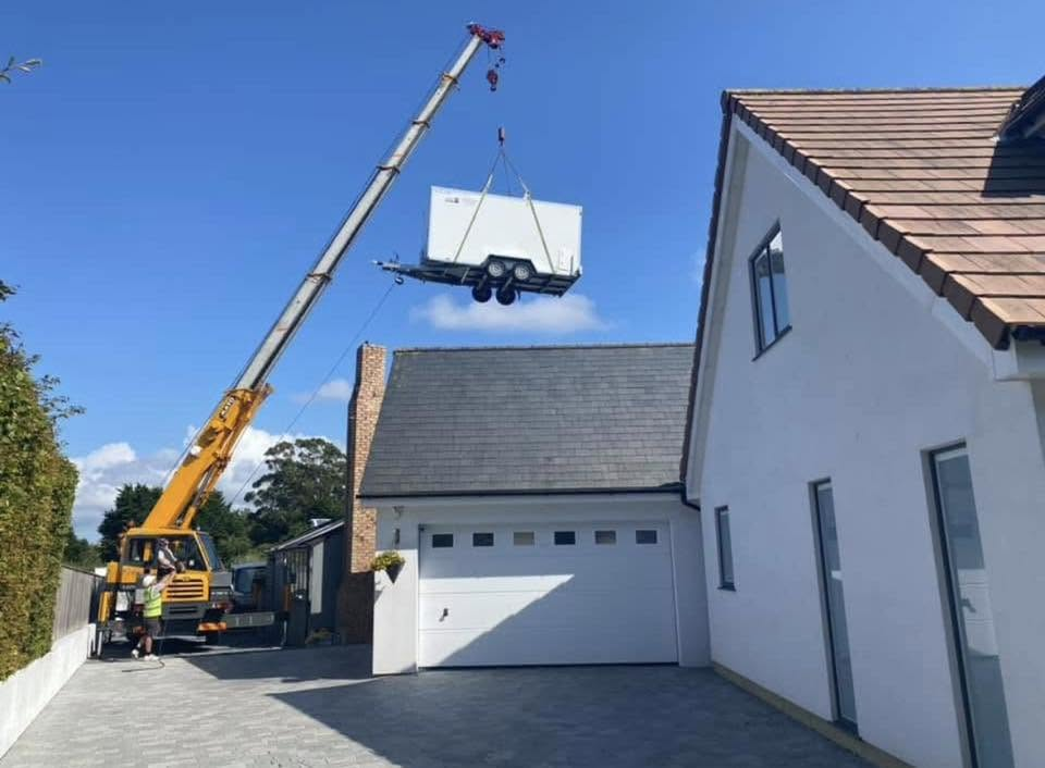 A pod being craned into place over a house