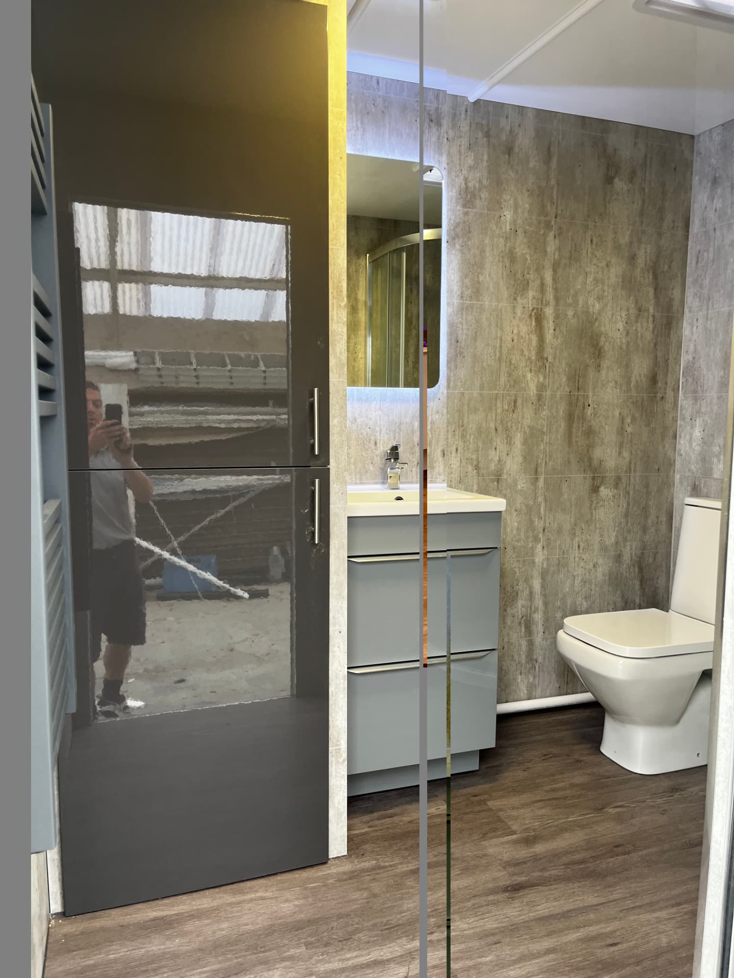 Inside a temporary shower pod with tall storage cupboard, vanity unit and toilet
