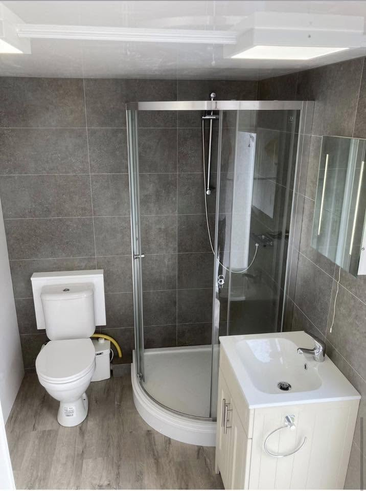 Inside a temporary shower pod with corner shower, toilet and basin