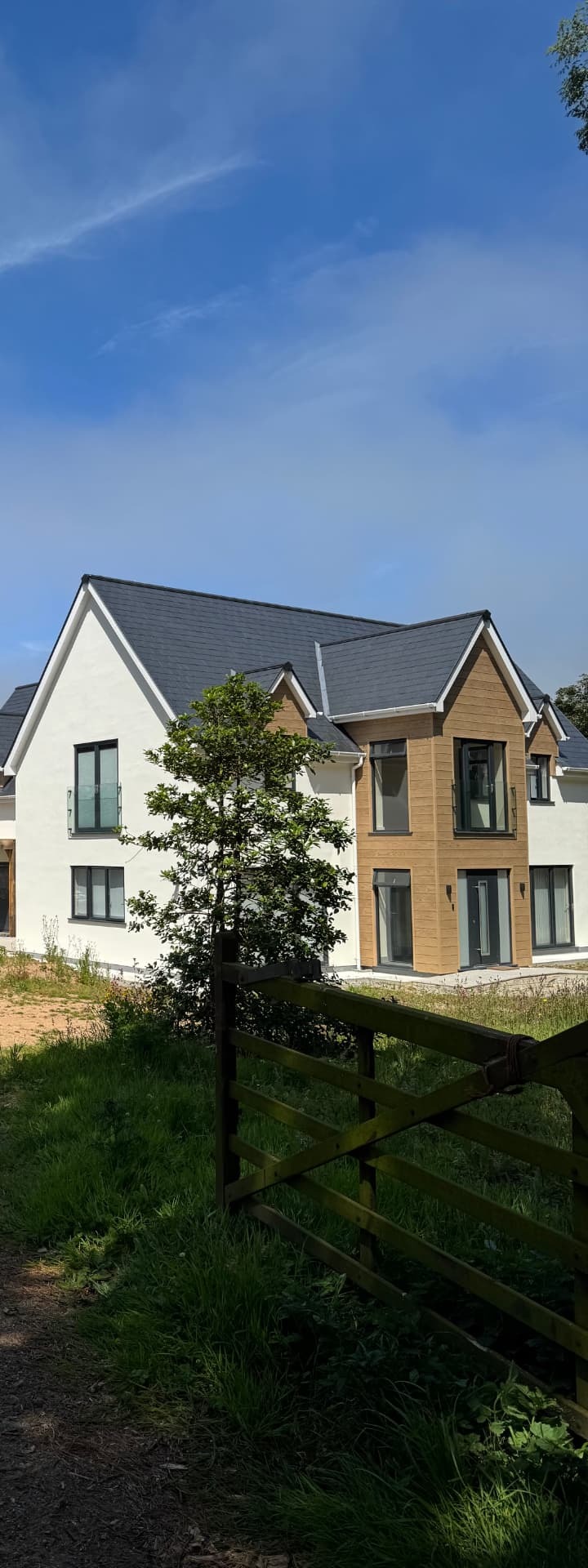 Wide view of the finished newbuild homes next to the restored stone barn