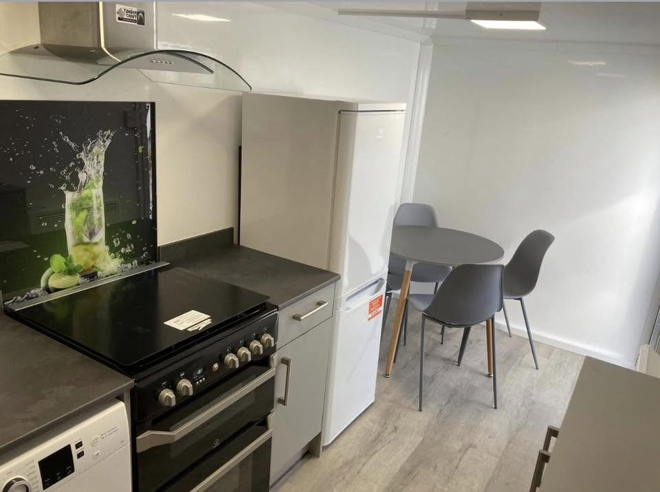 Temporary kitchen pod dining area with table, chairs and fridge/freezer