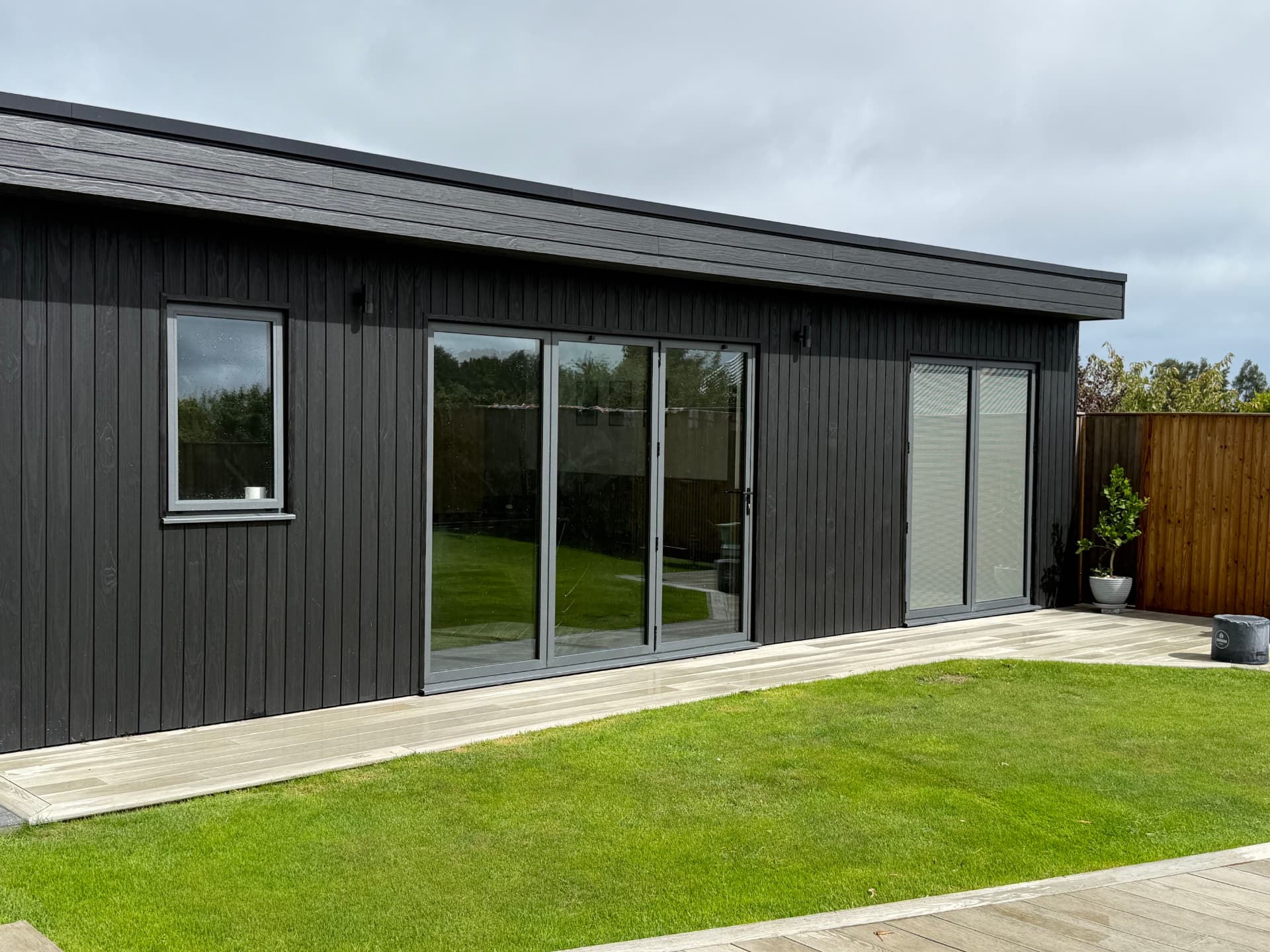 Finished black clad garden room with sliding doors onto composite decking