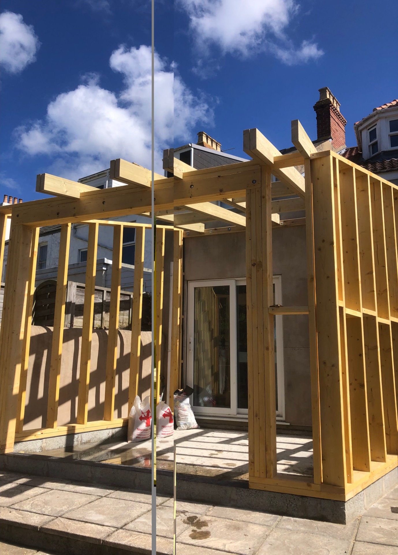 Timber frame extension being built with stud walls and roof beams in place