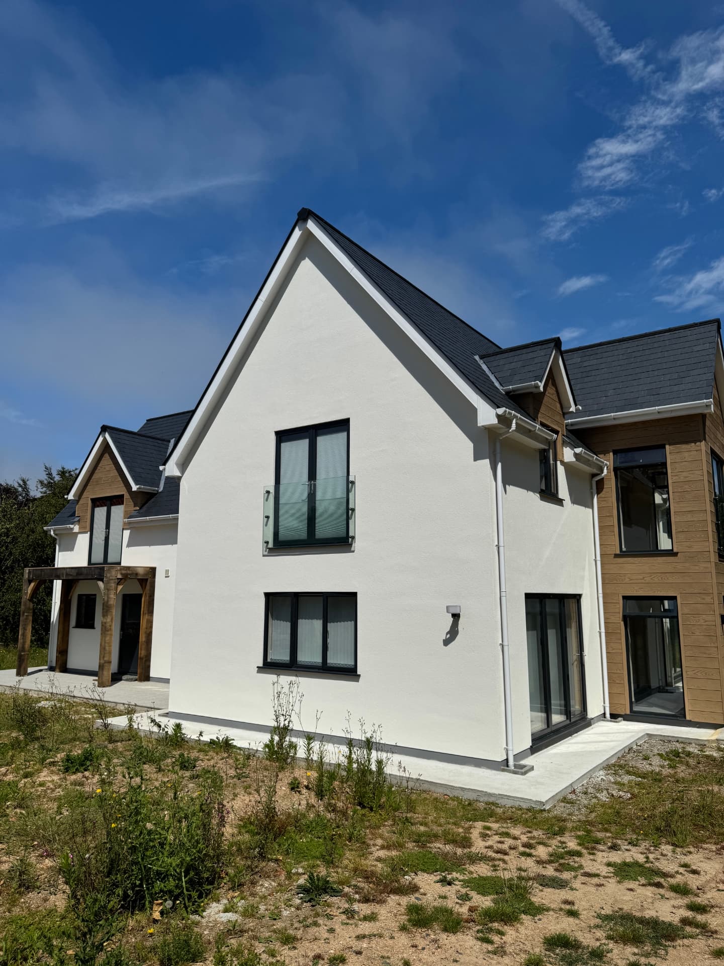 Gable end of the finished newbuild with juliet balcony and oak porch beyond