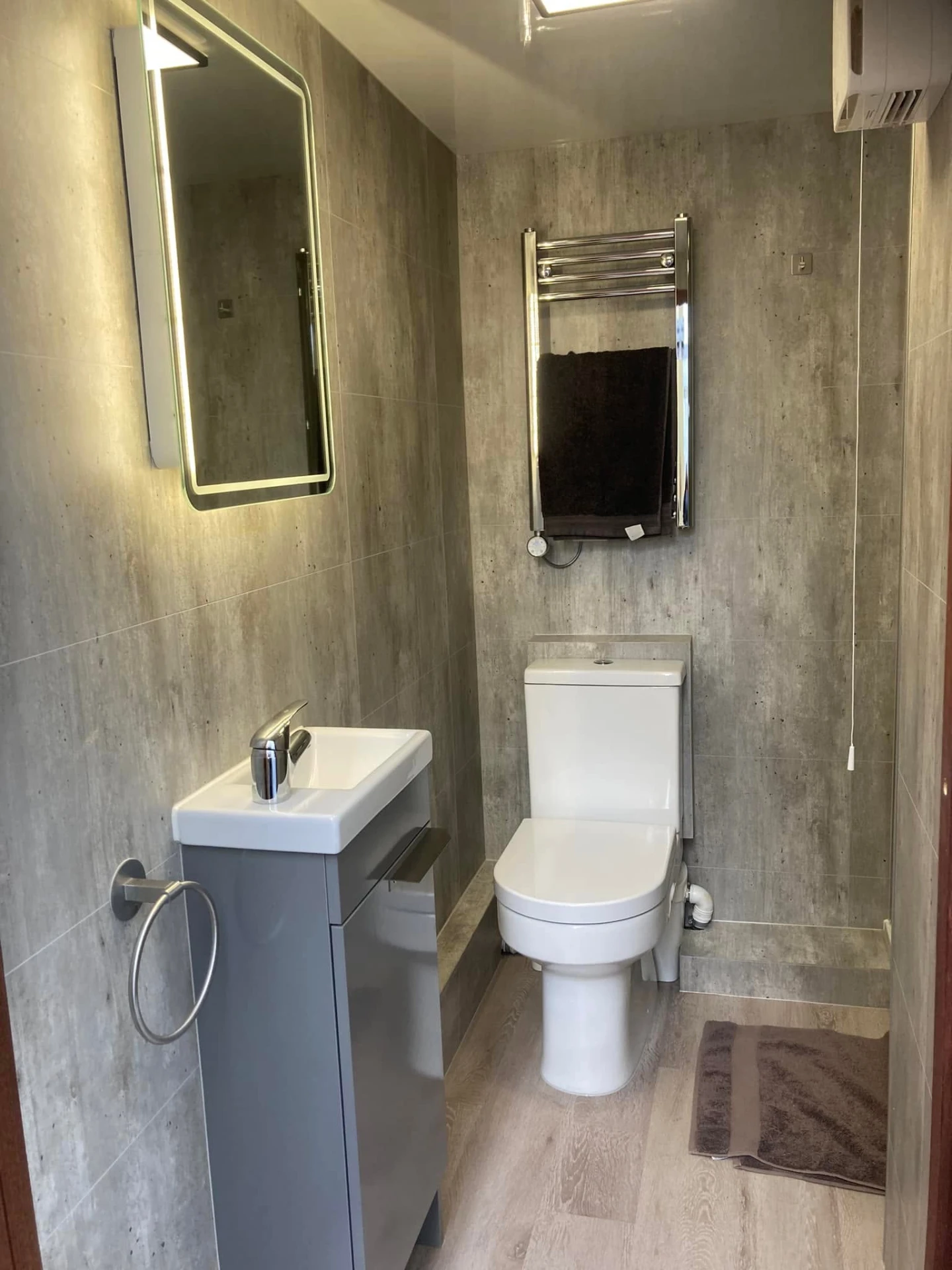 Inside a Timber Craft bathroom pod - toilet, vanity basin, LED mirror and heated towel rail