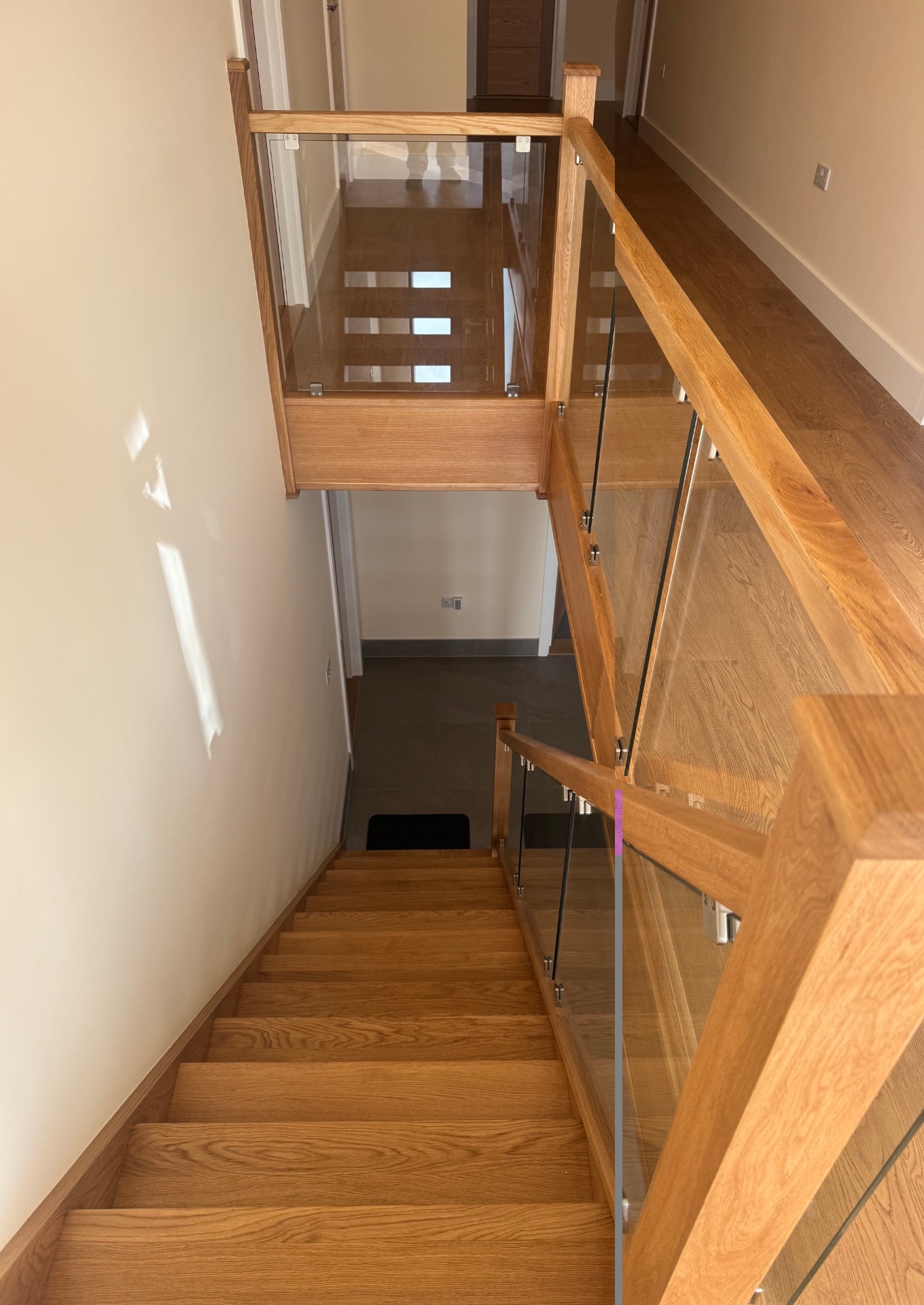 Oak staircase and first floor landing with glass balustrade viewed from above