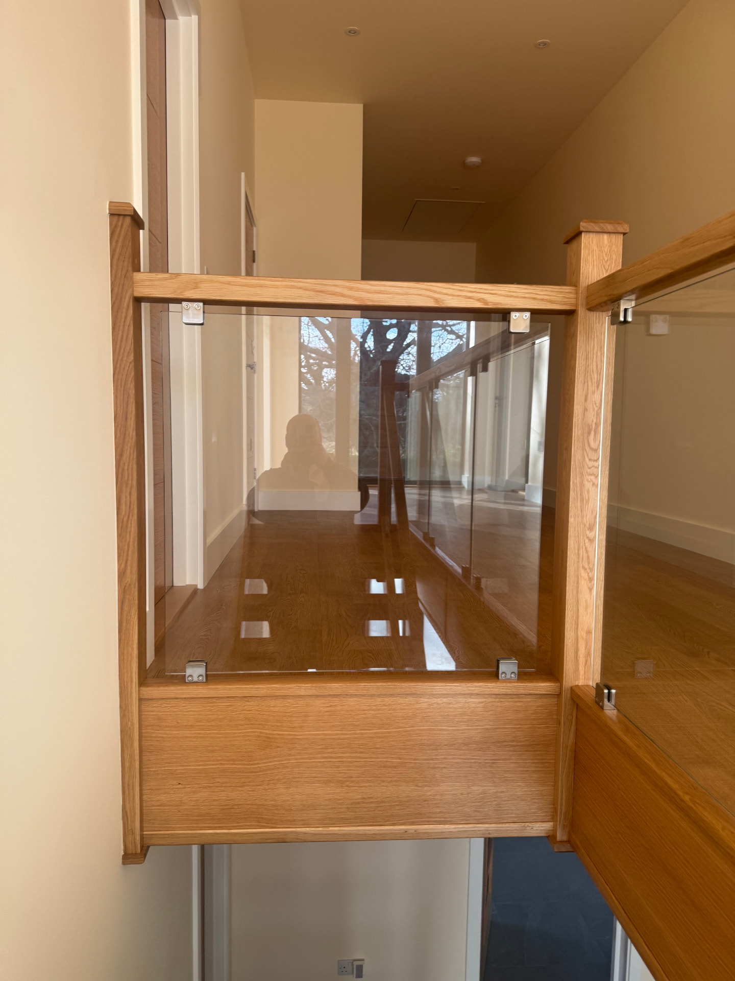 Oak landing gallery with frameless glass balustrade and oak newel posts
