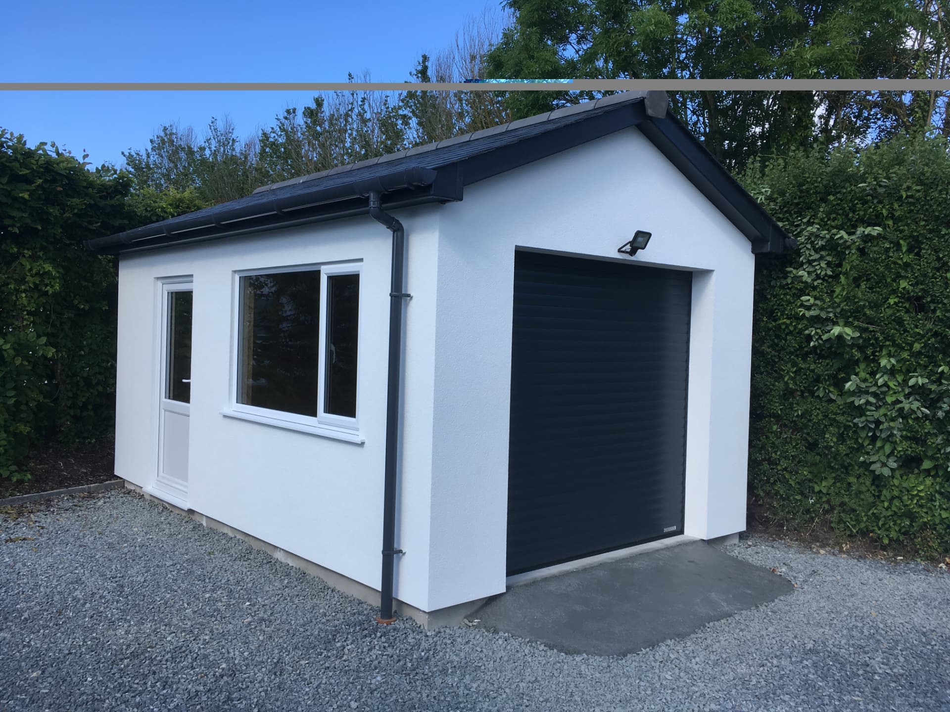 A newly built rendered garage with roller shutter door